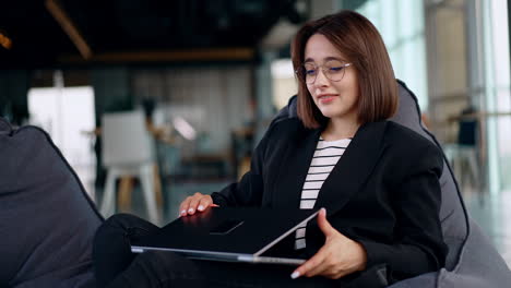 freelancing lady working in the comfortable place on her laptop. woman finishes her workday, closes laptop and leans in the chair relaxed.