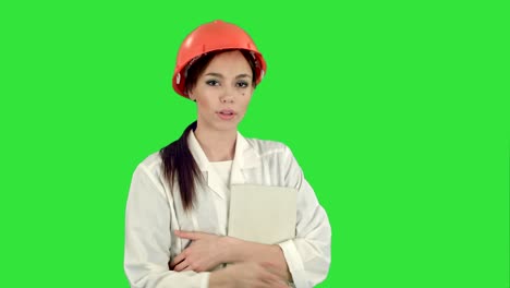 female architect in hardhat holding tablet talking to camera on a green screen, chroma key