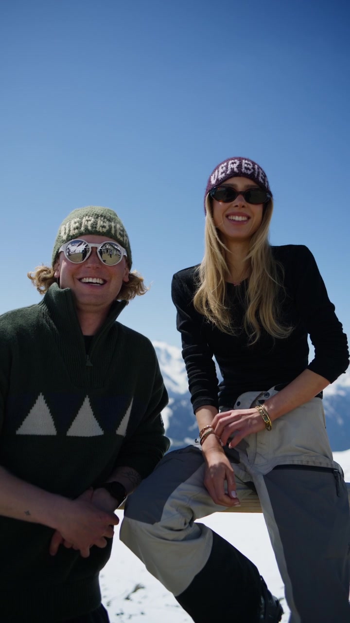Ungt par slapper af ved Cabane Mont Fort i Verbier, Schweiz, og nyder panoramaudsigt over de schweiziske alper på en solrig forårsdag. Alpestil, skisportsstedsturisme og scene for bjergrejser.