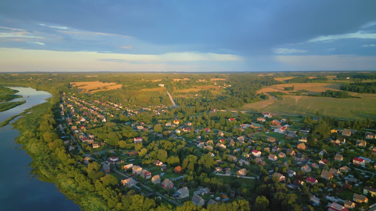 pintoresco pueblo en las afueras de daugavpils a orillas del río daugava al atardecer rodeado de vegetación, vista aérea