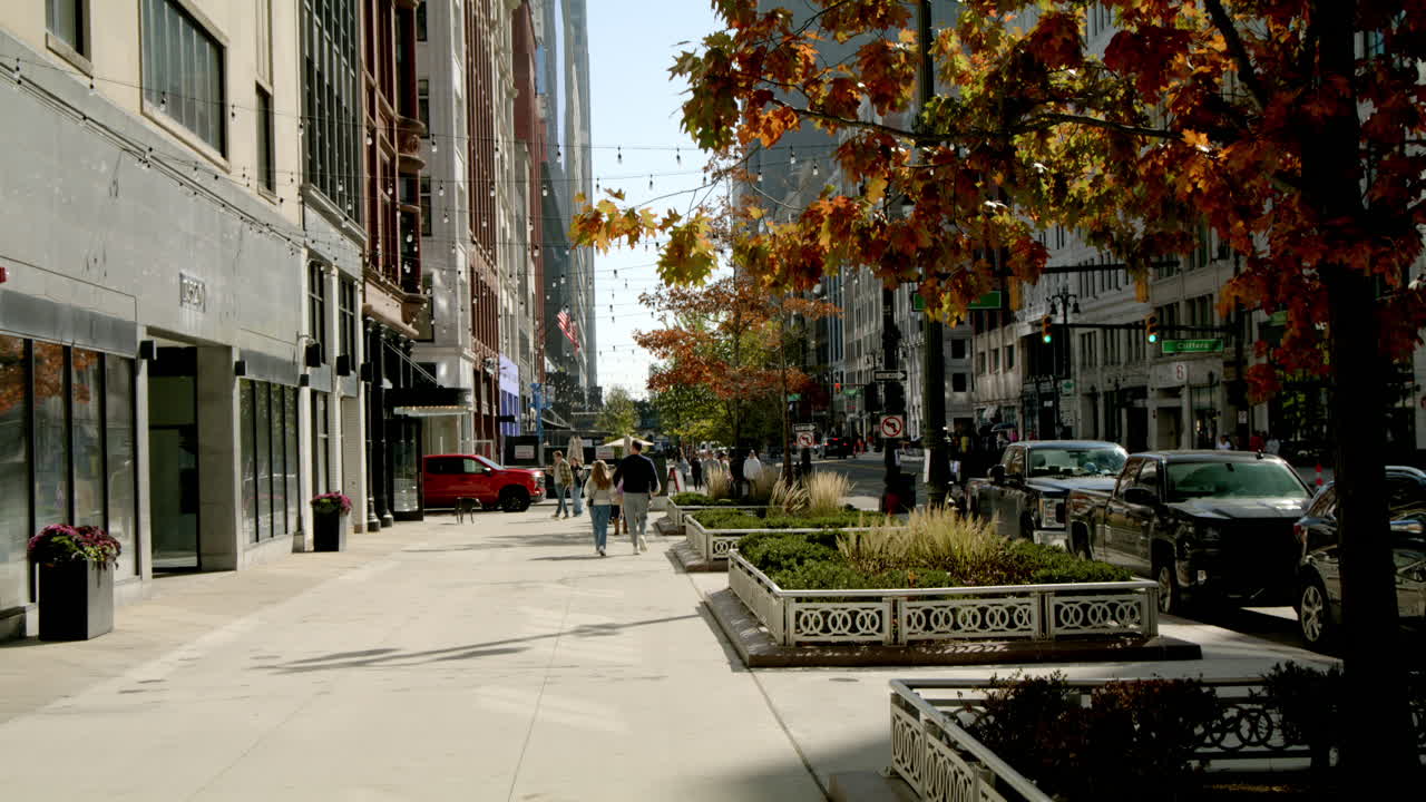 Pedestrians walking along Woodward Avenue in downtown Detroit, Michigan with video tilting down.