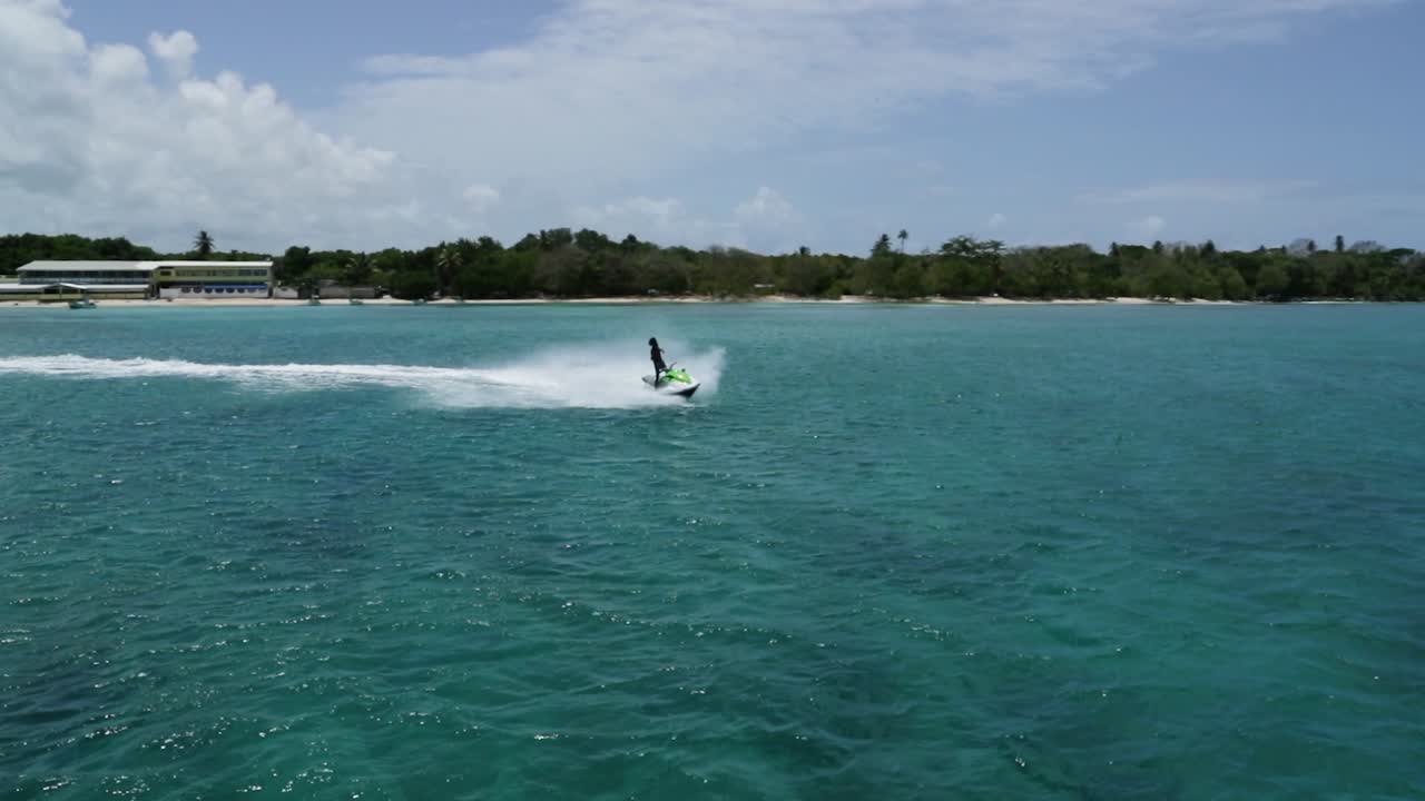 Jetski cruising towards a boat in the middle of the Caribbean off shore from Tobago, West Indies.