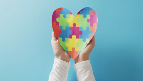 video de manos sosteniendo un rompecabezas corazón sobre fondo azul con espacio de copia