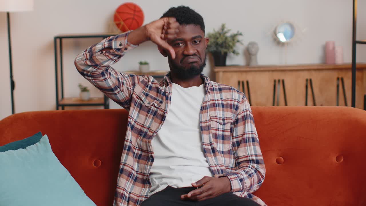 Teen guy showing thumbs down sign gesture expressing discontent disapproval dissatisfied dislike