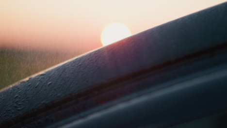 coche se encuentra bajo la lluvia pulveriza el anochecer sol primer plano coche negro con pequeñas gotas de agua en la tormenta de lluvia en