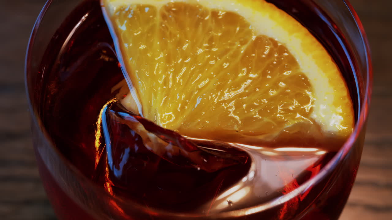 Close up of a Negroni cocktail with orange slice and ice cubes on a wooden table