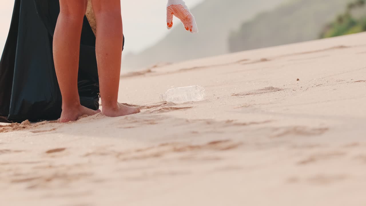 Woman lifting plastic bottle from ground for rescue beach and world ocean