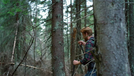 man with trekking poles hiking in forest. male tourist walking in green woods