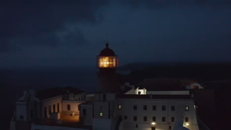 Scenic-aerial-drone-view-of-lonely-lighthouse-at-sunset-dusk,-circle-pan-reveal-background-sea-ocean,-Lagos-Algarve,-Portugal