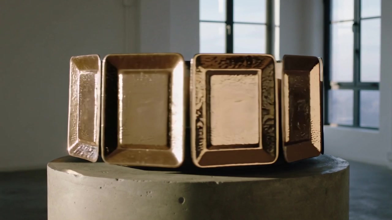 Rotating on turntable start, four gold blocks revealing shifting highlights on plinth in gallery