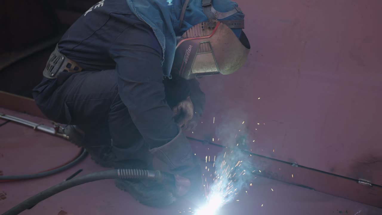 Masked man working on a shipyard with welding machine