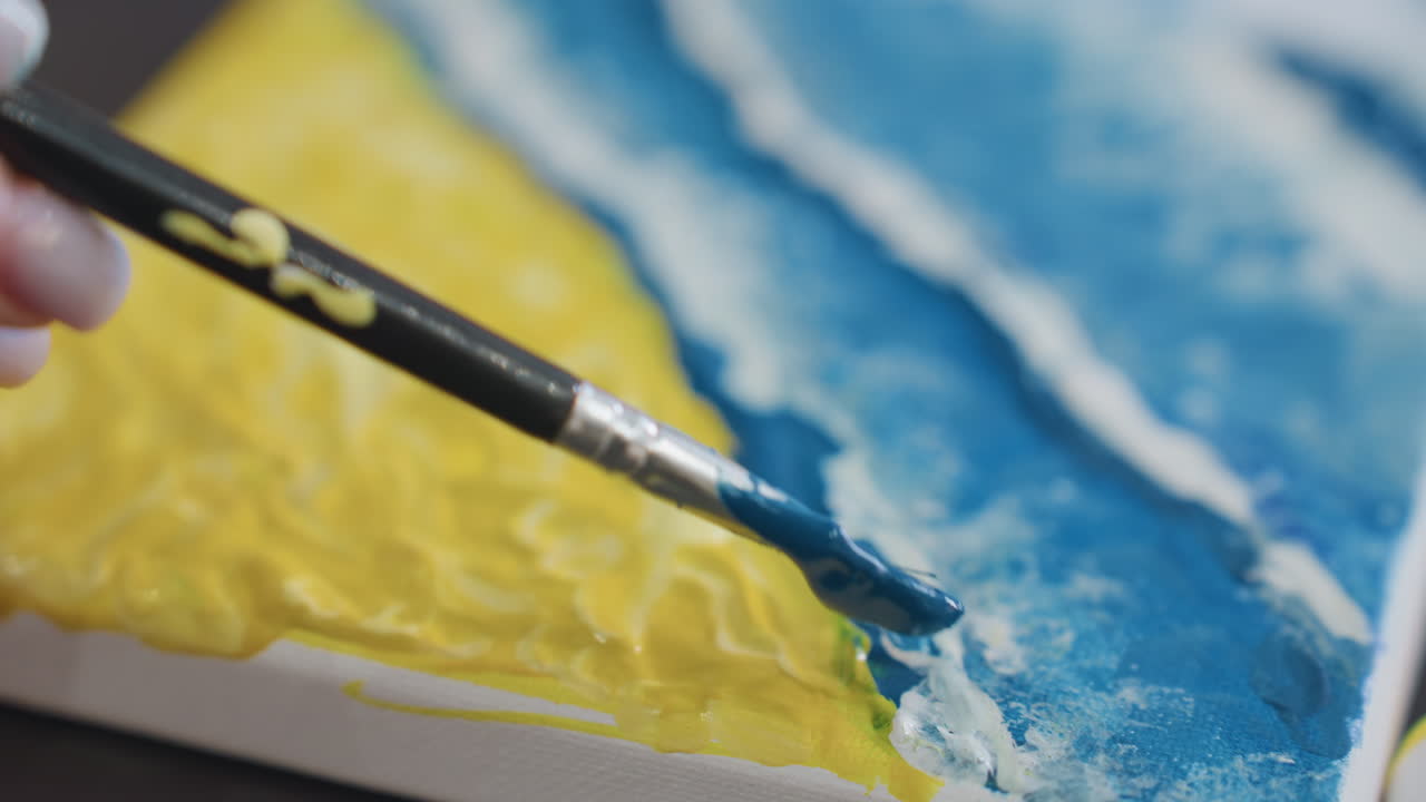질감 있는 캔버스에 색상을 혼합하는 섬세한 브러시워크, 겹쳐진 브러시 스트로크와 생생한 색상으로 묘사된 바다 풍경, 해안 장면 텍스처를 만들기 위해 파란색을 노란색 위에 칠하는 화가의 클로즈업