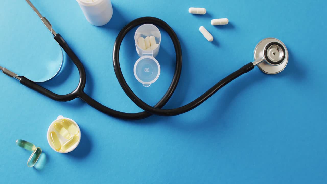 Video di stetoscopio con pillole e capsule su sfondo blu con spazio per il testo