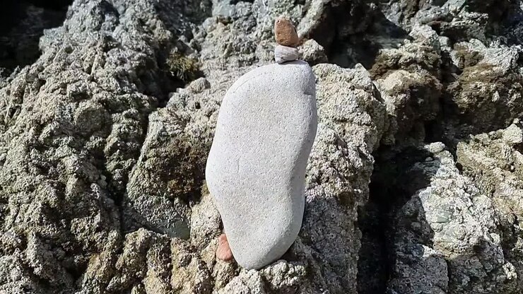 Balanceret zen-lignende stenbunke af småsten stablet på barske strandklipper ved solopgang