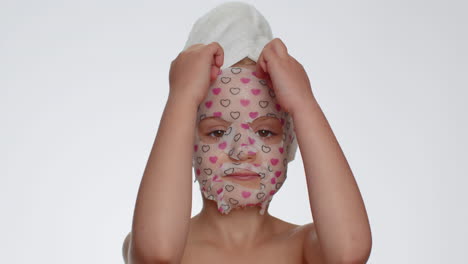 child girl removing cosmetic moisturizing face mask, teenager skin care treatment, natural cosmetics