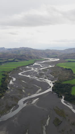 vertical drone shot flying along the waiau river, cloudy day in new zealand