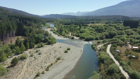 aerial dolly in of rio azul river flowing in valley surrounded by pine trees and mountains, patagonia argentina