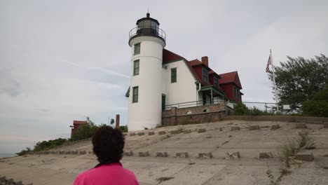 Mujer-Caminando-Y-Mirando-El-Faro-De-Point-Betsie-A-Lo-Largo-Del-Lago-Michigan-En-Frankfort,-Michigan-Con-Video-Cardán-Detrás