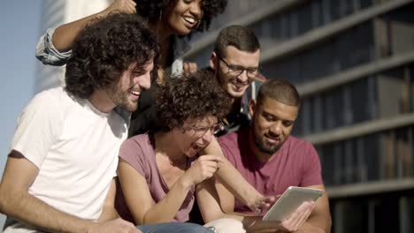 Happy-friends-looking-at-tablet-and-laughing.