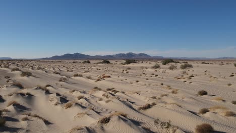 Vista-Aérea-De-Dunas-De-Arena-En-El-Desierto,-Montañas-En-Segundo-Plano