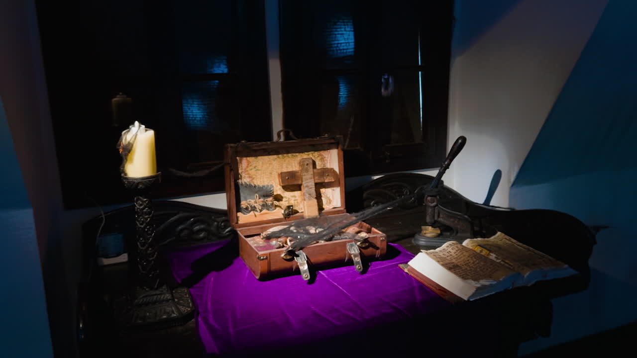 Old wooden suitcases with cross, thick book and candle in the room with dim light. Showpieces exhibited at Bran castle, Romania.