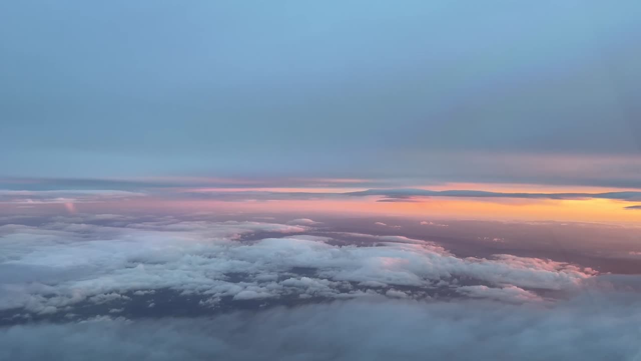 vista aérea desde una cabina volando entre capas de nubes al atardecer, con un cielo naranja