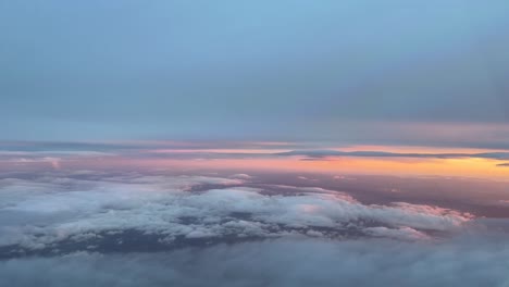 aerial view from a cockpit flying between layers of clouds in the sunset, with an orange sky