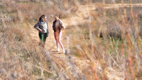 dos amigas toman un descanso durante una sesión de entrenamiento en el campo, a través de los arbustos