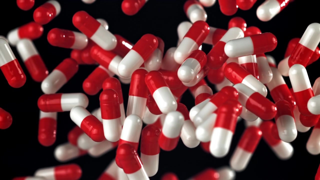 Red and White Medical Capsules Falling and Floating in Slow Motion