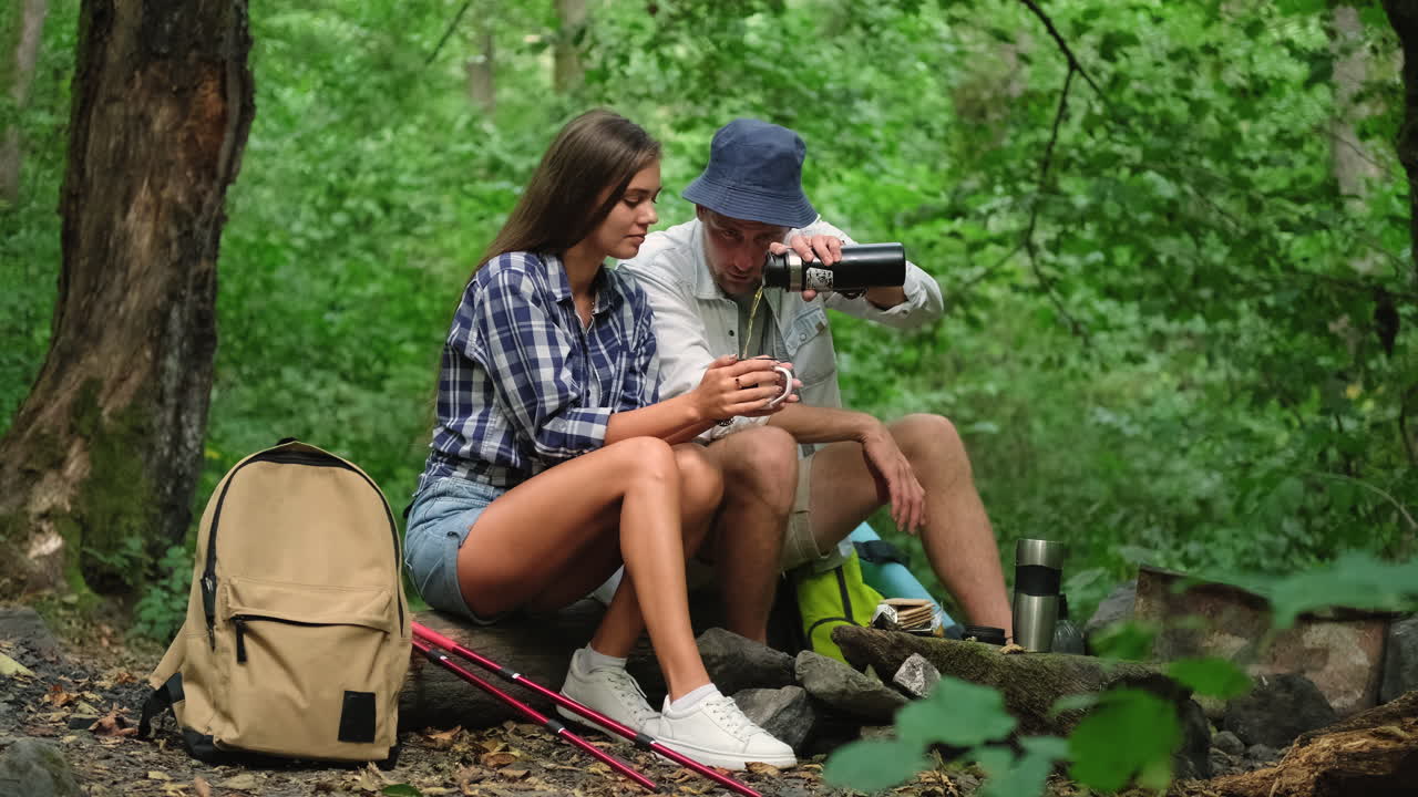 una pareja disfrutando de una bebida caliente en el bosque.