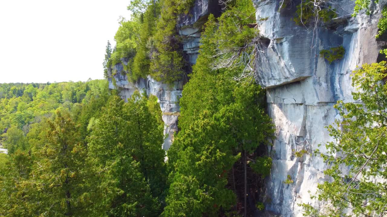 vuelo dinámico a lo largo de altos acantilados sobre las copas de los árboles, revelando el lago huron