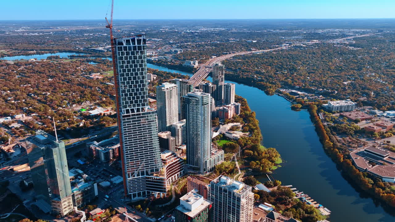Austin, EE. UU., 21 de noviembre de 2025: Una grúa alta se alza junto al rascacielos en el centro de Austin, Texas, EE. UU. El río Colorado fluye a lo largo del paisaje urbano verde. Vista aérea.