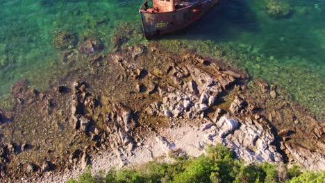 Reveal-shot-of-old-rusty-fishing-boat-shipwreck-on-shore-of-Kotor-Bay