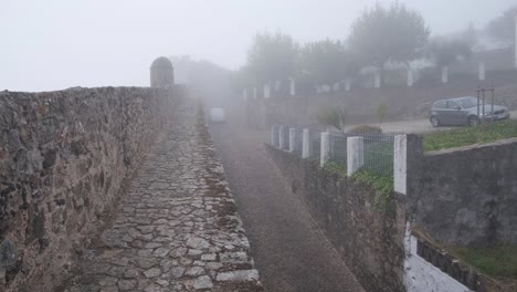 A-white-van-drives-up-a-mist-covered-road-to-Castle-Marvão