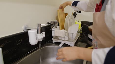 vista recortada de una persona lavando los platos en la cocina de la casa