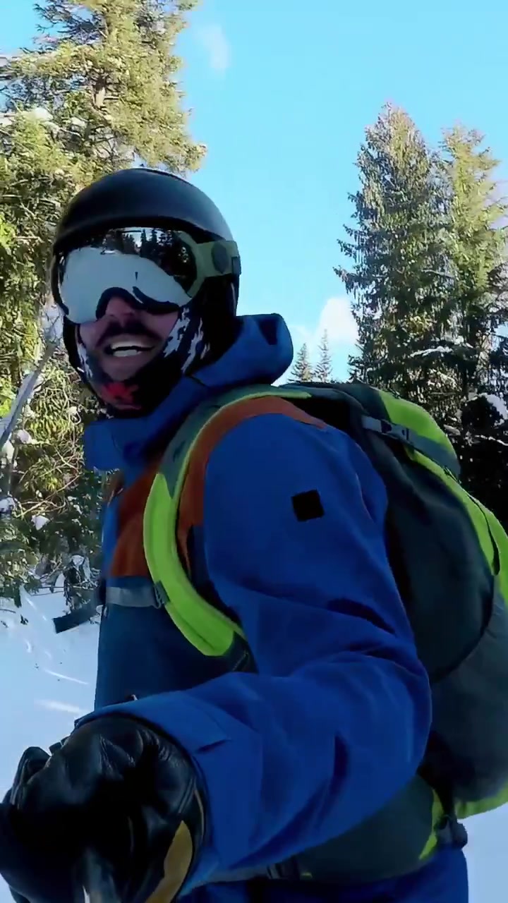 Video verticale: Uomo che scia, con un bastoncino, che effettua una curva e una chiamata su una pista innevata, con casco e spazio per il testo.