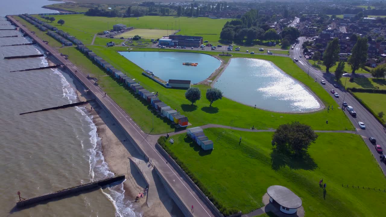 Breathtaking Coastal Drone View of Dovercourt&rsquo;s Vibrant Beach Huts, Verdant Sports Fields, and Tranquil Boating Lake
