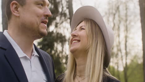 happy woman and man looking to each other and laughing while standing in the park