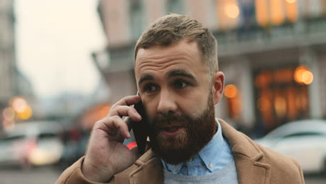 Close-up-view-of-caucasian-businessman-with-a-beard-talking-on-the-phone-in-the-street-in-autumn