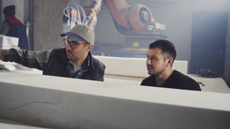 factory workers observing robotic foam cutting