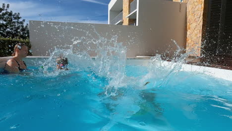 niño saltando a la piscina con la familia