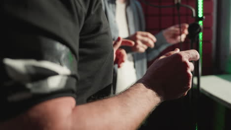 close-up of two men snapping their fingers rhythmically in a recording studio. one man wears a black shirt while the other is out of focus in the background