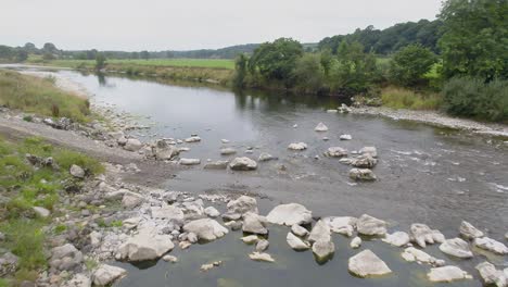 low and slow moving drone footage over a vehicle access track in a very calm river in the lake district countryside, uk