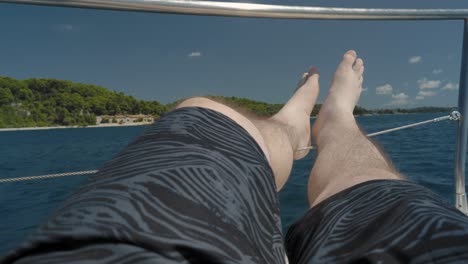 Hombre-Relajando-Sus-Piernas-En-El-Borde-De-Un-Barco-Durante-Un-Crucero-Cerca-De-La-Costa