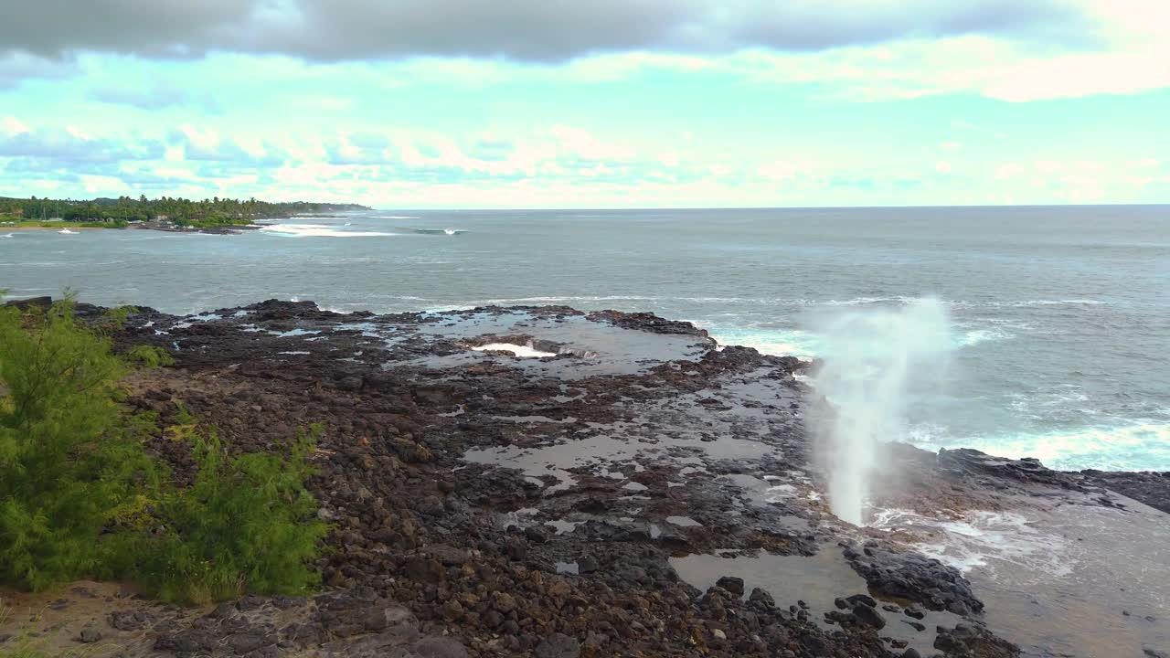 4K Hawaii Kauai pan left to right of Spouting Horn blowhole going off with ocean in distance and partly cloudy sky