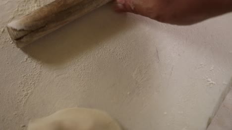 close up shot of a professional chef using a small roller to flatten dumpling dough