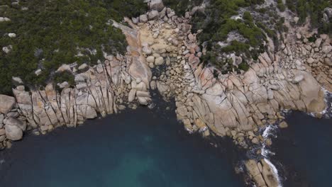 drone aerial looking down and spin over beautiful blue water and white rocks on a sunny day in wilsons promontory