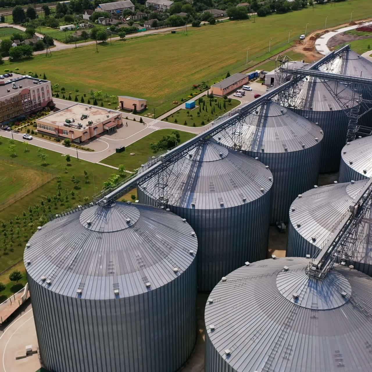 Extensive steel granaries for agribusiness in the field. Buildings and steel tanks at the territory of huge agricultural plant. Aerial view
