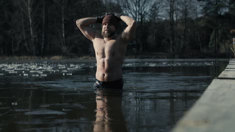 caucasian adult man going out of frozen lake in the winter.