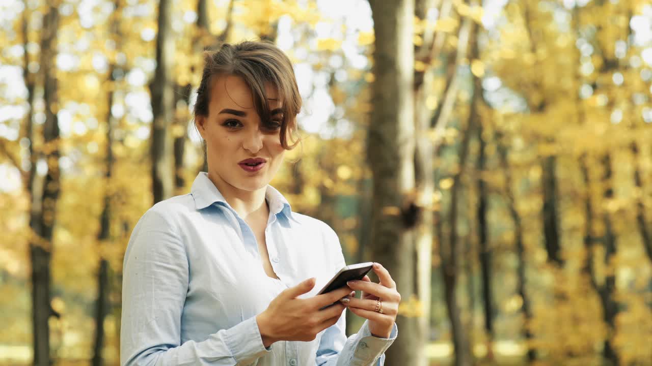 Girl with phone in park. Young woman speaking on mobile phone in park